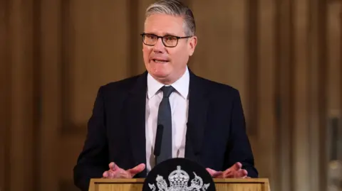 Prime Minister Sir Keir Starmer speaks in front of a podium at the start of a summit at Downing Street.