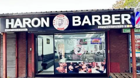 Google The outside of Haron Barber with sign and shop window.