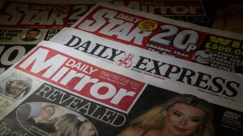Getty Images A pile of newspapers owned by Reach Plc - The Daily Mirror, Express, and Daily Star