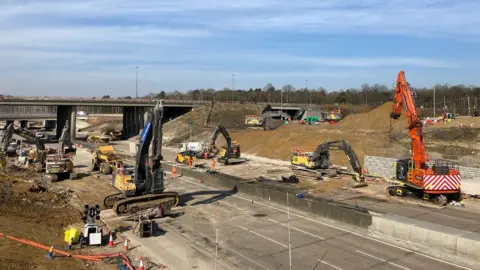 The M25 is closed to traffic while big machinery works on resurfacing the road. There are 6 diggers, excavators and a large workforce on site. 