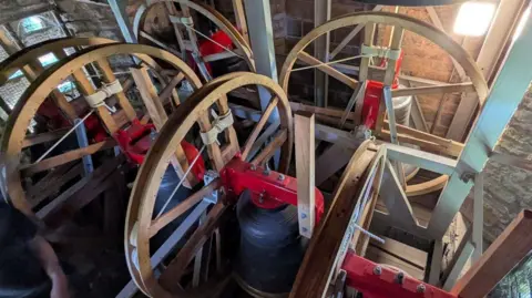 A set of church bells connected to large wheels in a church tower