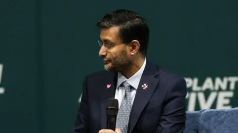 British Transplant Games Asian man in a dark suit holding a microphone