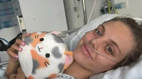 Freya is on a hospital bed with tubes up her nose and holding a cuddly toy.