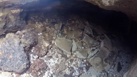 A view of stones and larger pieces of rock under the promenade at Hunstanton. The area should be solid rock but it has been eroded by the sea. 