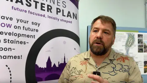A man with brown hair, beard and Hawaiian shirt. 