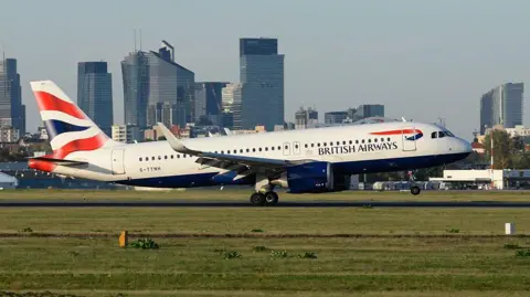A British Airways Airbus A320 aircraft lands with Warsaw's skyline in the background at the Warsaw Chopin International Airport