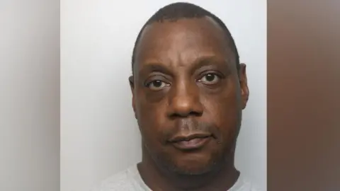 A mugshot of a man in a grey T-shirt looking at the camera.