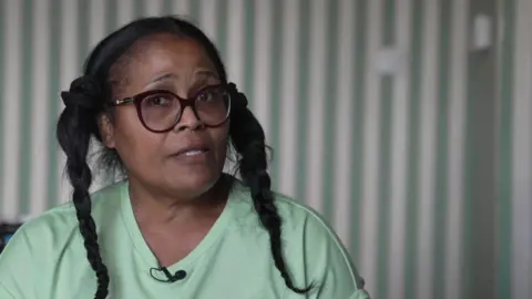 Ms Scott, a woman with dark hair in braids wearing a green t-shirt