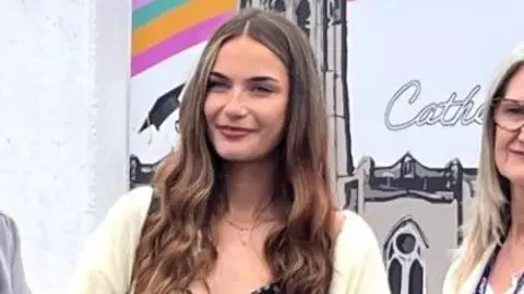 LJMU Alicia Woolley has a white cardigan and long brown curly hair in ringlet