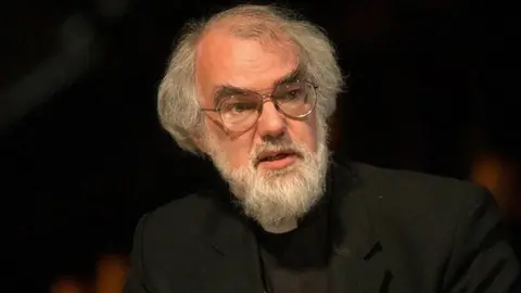 PA Media A man with grey hair and beard, wearing glasses and black attire with a white clerical collar 