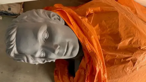 Peter Van Gelder The head of a Michael Jackson statue peeks out from under an orange sheet in a warehouse.