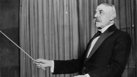 Composer Edward Elgar conducting with a baton