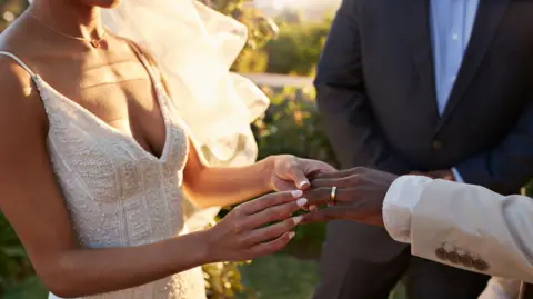 Getty Images A bride placed a wedding band on a groom's hand