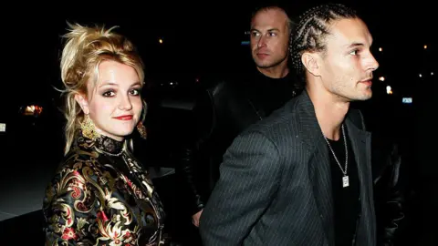 James Devaney via Getty Images Britney Spears and Kevin Federline are seen walking into an event. Britney is wearing a dress and Kevin is in a black T-shirt and jacket. 