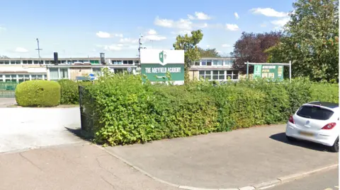 A view of Adeyfield Academy from the street. It is surrounded by a green shrub