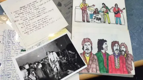 Nicky Weller A black and white photo, cartoon drawings and written notes scattered on a table which belong to Paul Weller during his formative years.