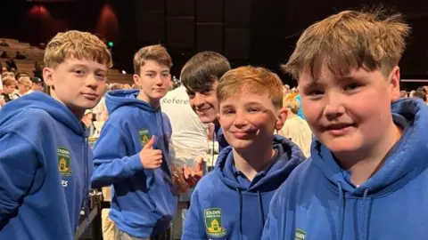 A group of five Teenage boys in blue hoodies that have the green and yellow Endon high badge on.