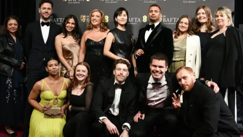 Franz Böhm Franz Böhm is among a group of 14 people, all dressed smartly and smiling, at the Bafta ceremony