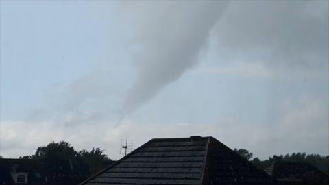 Funnel cloud hovering above a roof
