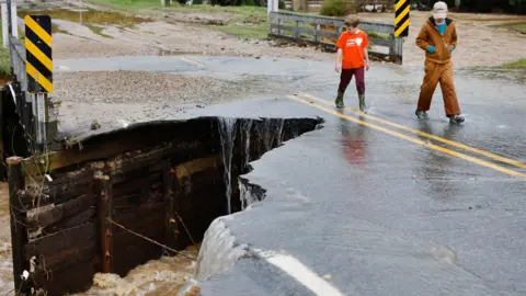 Reuters Children locomotion  past   the collapsed information   of a span  aft  flood waters destroyed it, successful  Boone, North Carolina