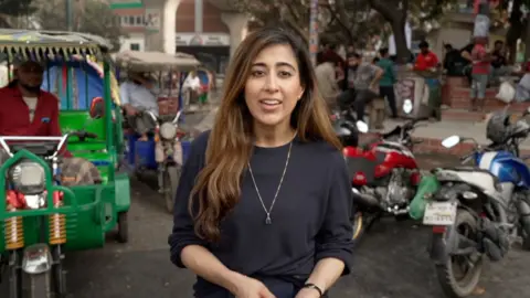 BBC correspondent Azadeh Moshiri standing in front of motor bikes on a street in Dhaka