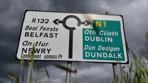 Reuters A road sign showing a roundabout. Pointing left is Belfast and right is Dublin. The sign is in both English and Irish. 