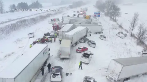 A group of trucks and cars in a collision on a snowy motorway.