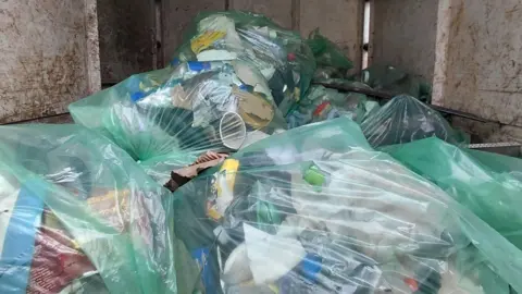 Green rubbish sacks stashed in the back of a van.