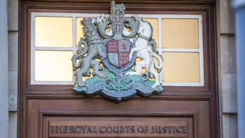Crest and the words of the royal courts of justice above a wooden door at the High Court in Belfast.