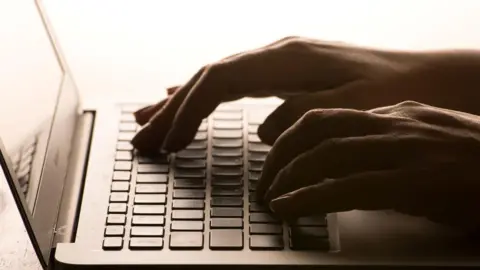 A pair of hands are typing on a laptop