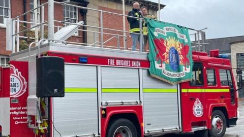 Fire engine with firefighters standing on top of it
