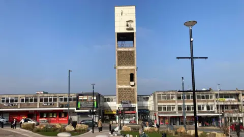 A six-storey concrete tower with parades of shops on either side