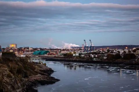 A look at the industrial port in the city of Saint John, New Brunswick, with the river and sky both prominent.