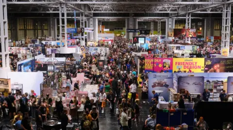UK Games Expo A large, crowded hall with people gathered around dozens of trade stands