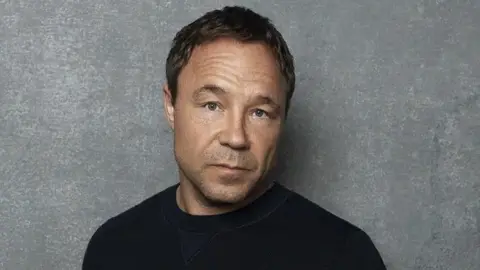 Joseph Sinclair Stephen Graham head and shoulders shot. He is wearing a black top.