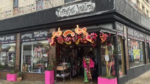 Cliftonville Junktion vintage shop on Northdown Road with pink planters outside the entrance and a sign in the window that reads 'Peace On Earth'