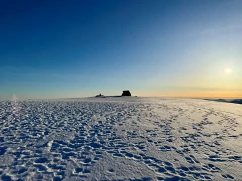 Bill Cameron Blue sky with a yellow sunrise and snow covered summit of Ben Nevis. 