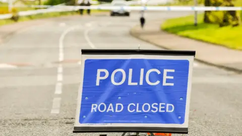 A police sign stating a road is closed after an incident.