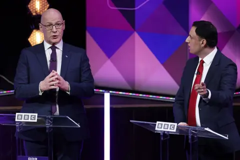 Getty Images Two men in suits having a debate as they are stood behind rostrums with the word bbc written on front 
