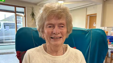 A woman with grey blonde hair wearing a cream jumper