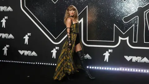 Getty Images Taylor Swift wearing a yellow and green tartan dress at the MTV 2024 Video Music Awards 