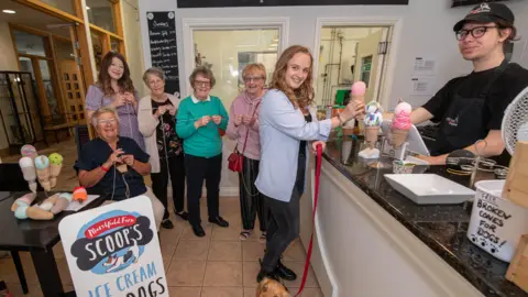 A group of volunteers are pictured in an ice cream parlour knitting ice creams