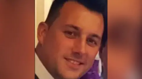 Family Photo Close up image of Christian Dean smiling. He is wearing a white shirt and has short black hair.