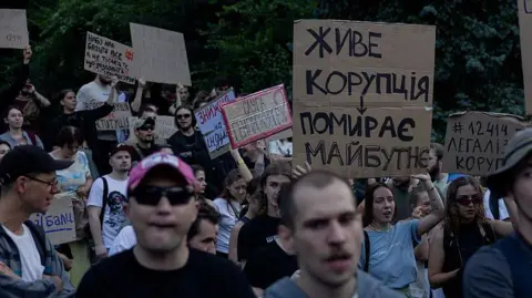 Getty Images Ukrainians stand in opposition in Kyiv to a new law - holding up placards