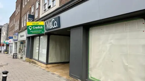 GEORGE CARDEN / BBC An empty M&Co with sheets in the windows. 