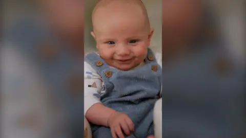 Baby Theo smiling at the camera 