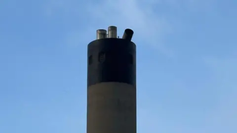 ANNEKA COLLINS The top of the stack, one of the flue caps has fallen over, on a clear day.