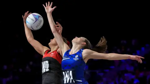 PA Media A Scotland player and Wales player compete for the ball during a netball match