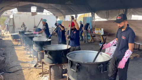 Cooks stir pots of rice and lentils at a community food kitchen run by the US-based humanitarian organisation Anera in Khan Younis, southern Gaza