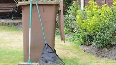 Middlesbrough Council Brown bin in a garden with gardening implements